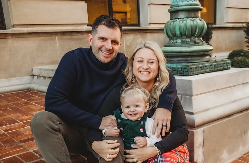 Jim and Amanda Hanus, owners of InterPeak, sitting on downtown steps with their son